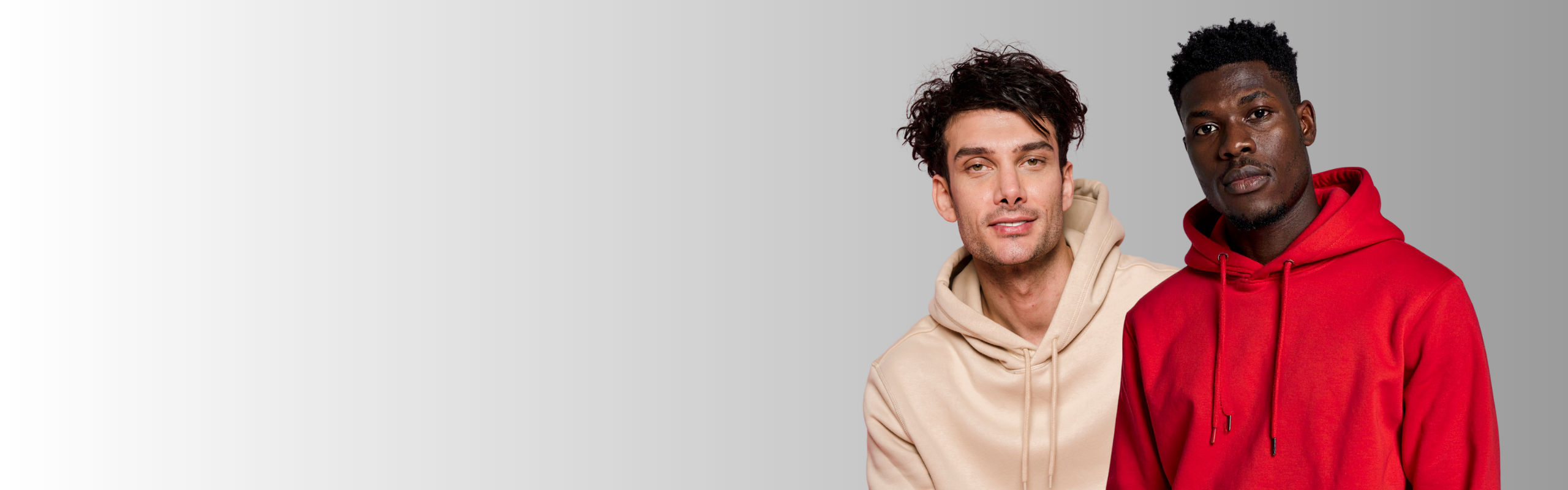 Two men wearing hoodies standing side by side against a plain background